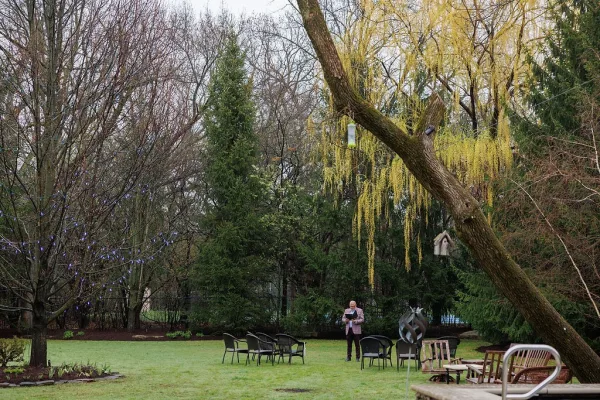 Wedding lounge setup for outdoor wedding seating beneath sweeping willow branches on a grass lawn, warmed by soft string lights at dusk.