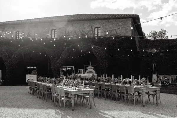 Reception tablescape featuring outdoor reception decor under glowing string lights in a courtyard beside an ivy-covered stone building.